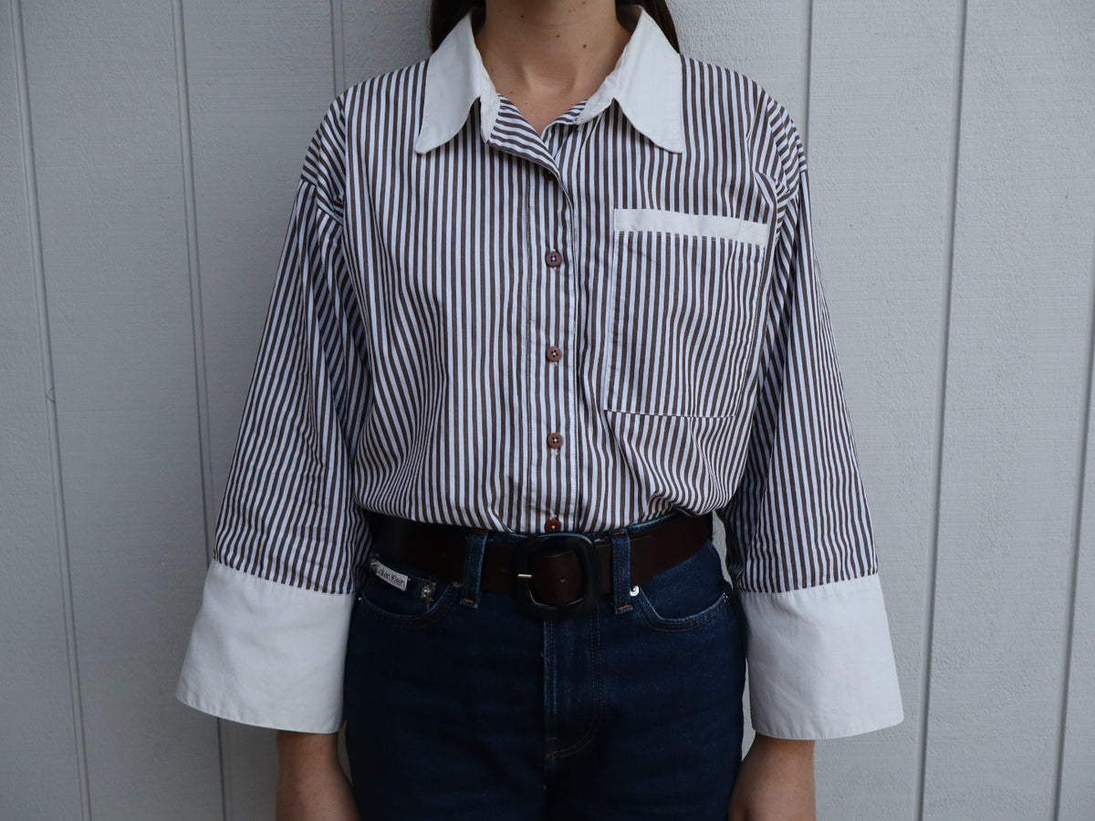 Woman wearing the Ruth shirt. An oversized collar shirt in brown and white stripe cotton with white organic cotton contrast cuffs and collar. 